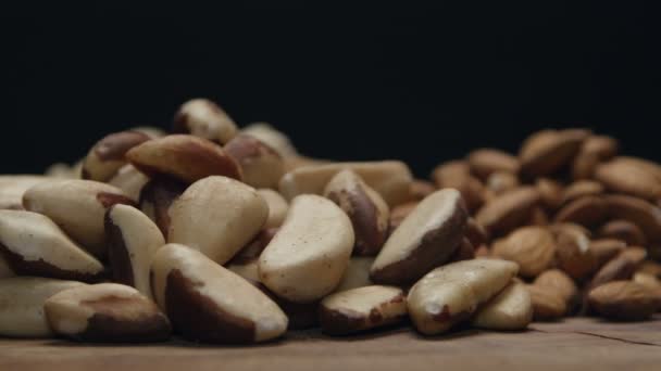 Haufen gemischter Nüsse auf einem Holztisch isoliert auf schwarz — Stockvideo