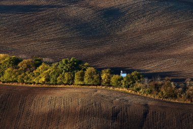 Küçük beyaz düğün Şapel sürülmüş alanlar arasında sonbaharda ağaçların arkasında gizli. Kyjov Güney Moravia.Czech Cumhuriyeti.