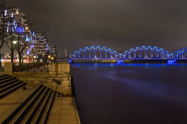 Słynny most kolejowy przez rzekę Dźwina w nocy w Rydze. — Zdjęcie stockowe