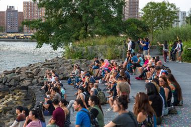 Brooklyn Bulvarı'nda oturan ve izlerken günbatımı insanlar.