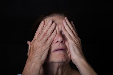 Yaşlı kadın portresi. Elleriyle gözlerini kapatır