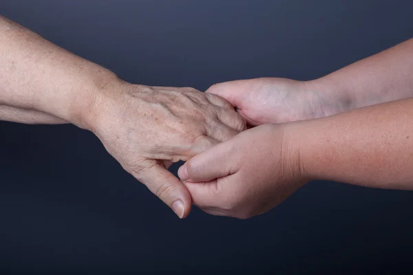 Handen van ouderen en jonge vrouwen op zwarte achtergrond — Stockfoto