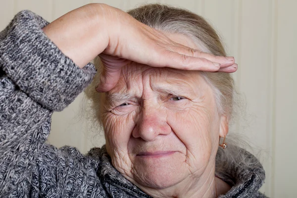 Portrait of an elderly woman with hand near face on a light back