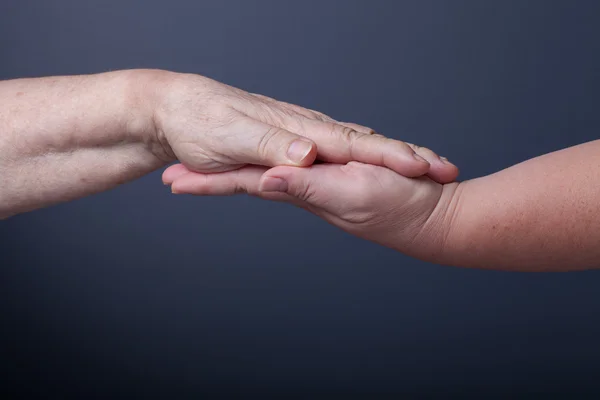 Handen van ouderen en jonge vrouwen op zwarte achtergrond — Stockfoto