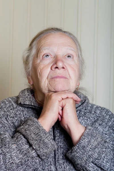 Portret van een oudere vrouw met handen in de buurt van gezicht op een lichte bac — Stockfoto