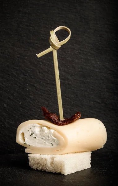 Pequeños rollos con queso y tomate seco en pincho sobre un sl negro — Foto de Stock