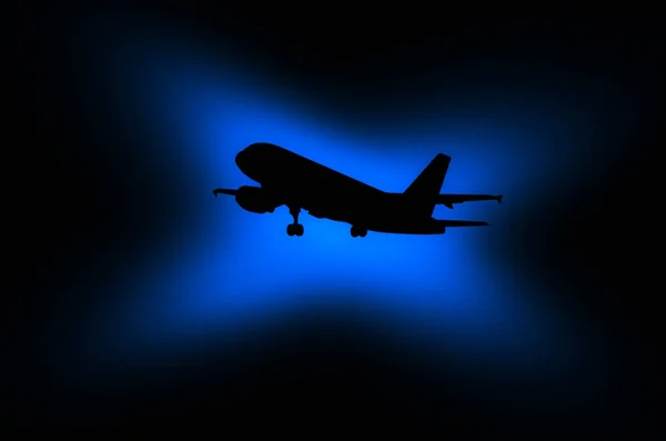 Black silhouette of an airplane on a dark background with a shin — Stock Photo, Image