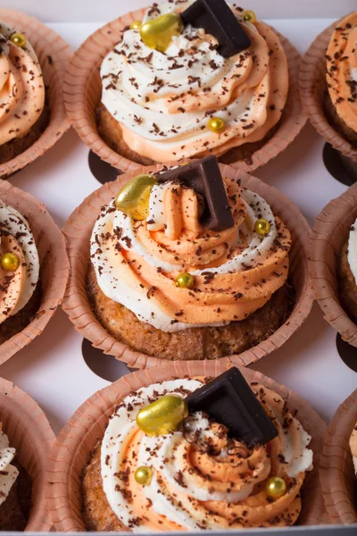 Cupcakes de baunilha com creme de queijo laranja e branco e chocolate — Fotografia de Stock