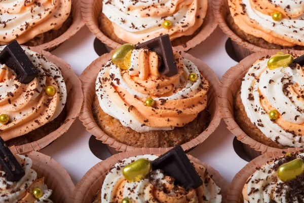 Cupcakes de baunilha com creme de queijo laranja e branco e chocolate — Fotografia de Stock