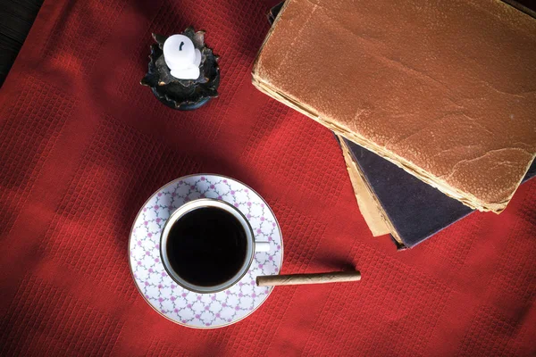 Oude boeken, kopje koffie, sigaretten en oude kaars op de re — Stockfoto