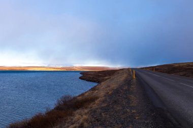 İzlanda 'nın doğusundaki fiyordun kıyısında asfalt yol.