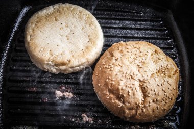 Susam çörek bir tavada ızgara. Malzemeler jambon için hazırlanıyor