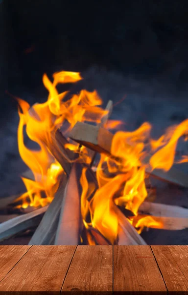 Uitzicht vanaf de houten tafel naar heldere vlam van vuur. Collage. Defo — Stockfoto