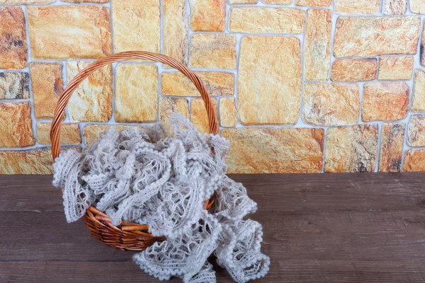 Knitted scarf in the basket and two color candles on wooden tabl — Stock Photo, Image