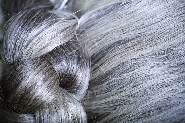 The hair of an elderly woman is gathered at the back of the head