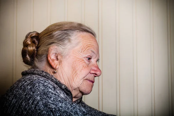 Portrait of an elderly woman on a light background. Thoughtful p — Stock Photo, Image