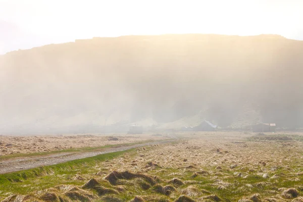 De weg van grind en meerdere kleine huizen in een dikke mist over de sh — Stockfoto