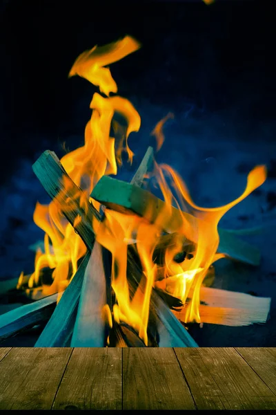 Vue de la table en bois à la flamme vive du feu de joie. Collage. Défaut — Photo