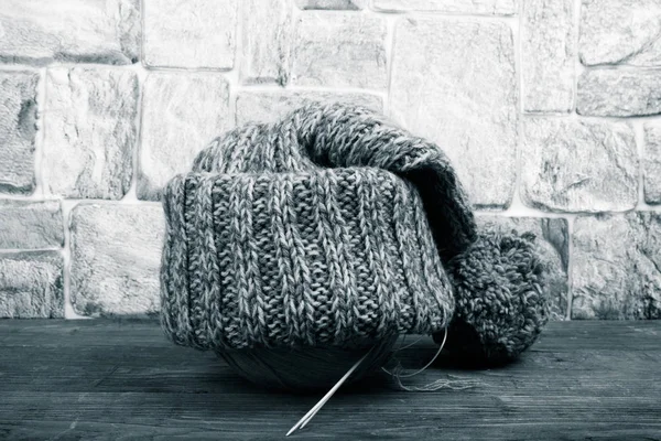 Sombrero de punto hecho a mano en una mesa de madera oscura frente a la pared de piedra . —  Fotos de Stock