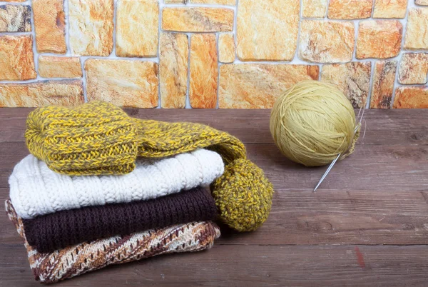 Stack of knitting clothes, homemade hat and ball of yarn with kn — Stock Photo, Image