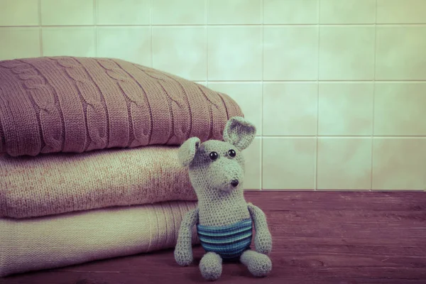 Knitted toy mouse or rat with the stack of knitted clothes on wo — Stock Photo, Image