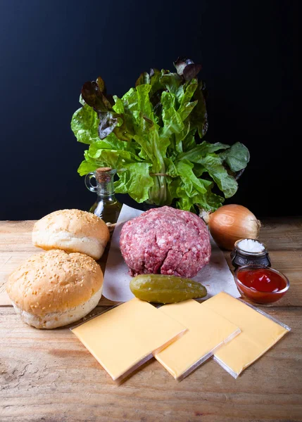 Carne, queso, cebollas, hierbas, sal, ketchup en una mesa de madera — Foto de Stock