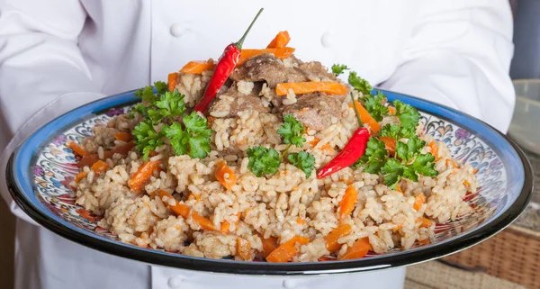Dish with pilaf in the hands of the cook — Stock Photo, Image
