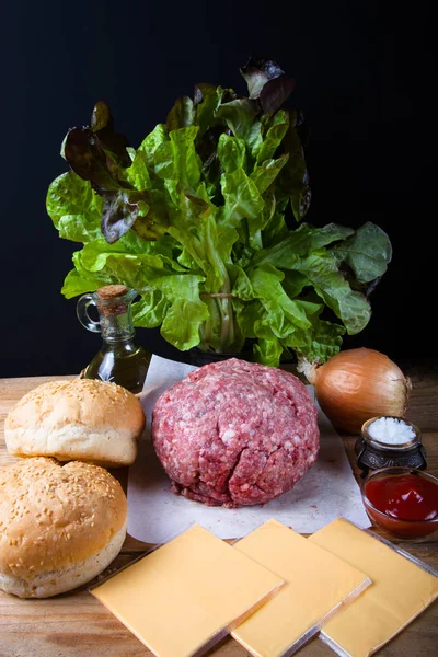 Carne, queso, cebollas, hierbas, sal, ketchup en una mesa de madera — Foto de Stock