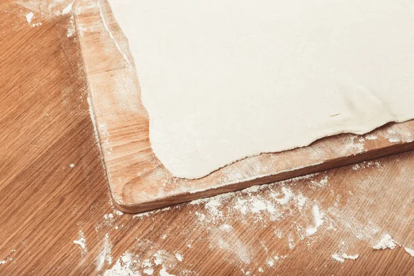 Massa de farinha de sopro, tábua de corte de madeira em uma mesa leve com farinha. Para — Fotografia de Stock