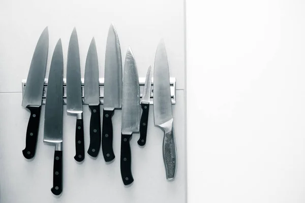 Cuchillos de cocina fijados en un imán en una pared de luz para el fondo. T —  Fotos de Stock