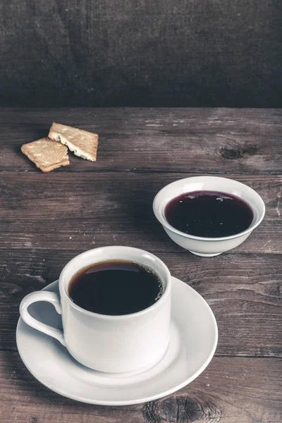 Xícara de chá com geléia e biscoitos na velha mesa de madeira contra o — Fotografia de Stock