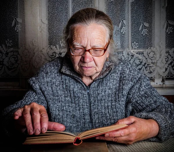 Äldre kvinna läser bok i rustik inredning. Tonas — Stockfoto