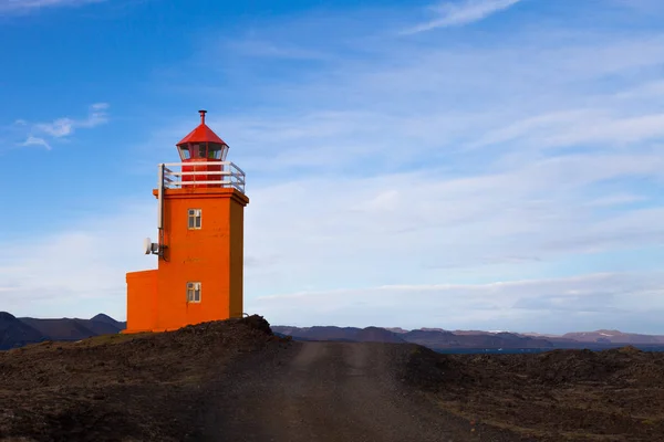 आइसलँडमधील दगड किनारपट्टीवर ऑरेंज लाइटहाऊस — स्टॉक फोटो, इमेज