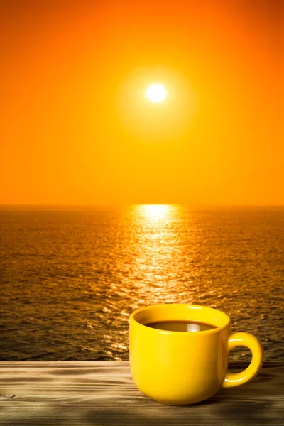 Kaffee oder Tee in gelber Tasse auf dem Holztisch gegenüber der Meeressonne — Stockfoto