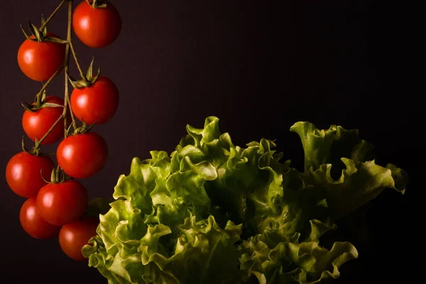 Куча свежих помидоров черри и зеленый салат на черном бэкгре — стоковое фото