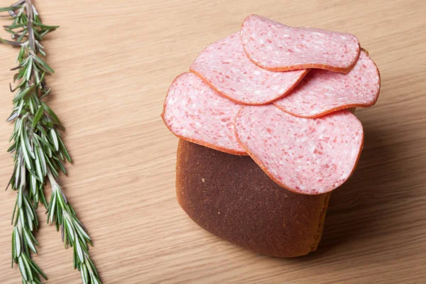 Kolbász és a kenyér, a piros chili paprika egy könnyű fából készült asztal — Stock Fotó