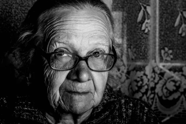 Elderly woman with glasses in rustic interior. Toned — Stock Photo, Image