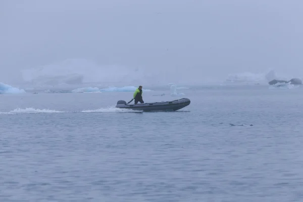 Mann auf einem Boot zwischen bizarren Eisschollen der Eisberg-Lagune — Stockfoto
