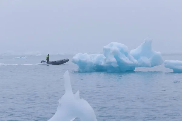 Mann auf einem Boot zwischen bizarren Eisschollen der Eisberg-Lagune — Stockfoto