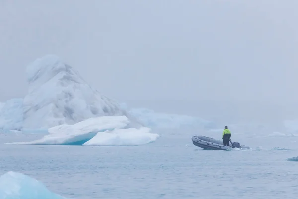 Mann auf einem Boot zwischen bizarren Eisschollen der Eisberg-Lagune — Stockfoto
