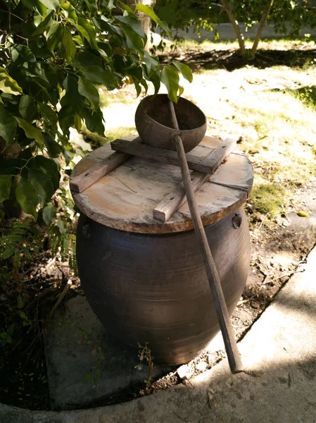 Barril de arcilla y medio cucharón de coco cerca de la cabaña en un territorio de ho — Foto de Stock