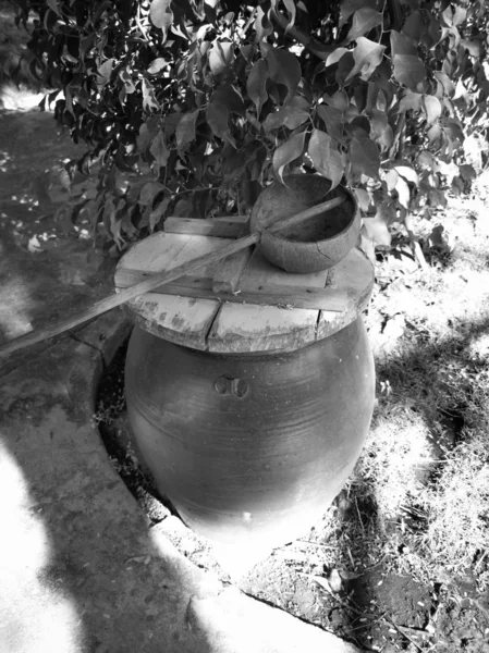 Baril d'argile et demi louche de noix de coco près de la cabane sur un territoire de ho — Photo