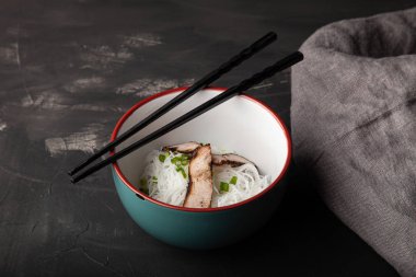 Bir kase pirinç eriştesi, et ve sebzeli kompozisyon.