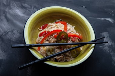 Bir kase pirinç eriştesi, et ve sebzeli kompozisyon.