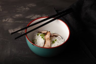 Bir kase pirinç eriştesi, et ve sebzeli kompozisyon.