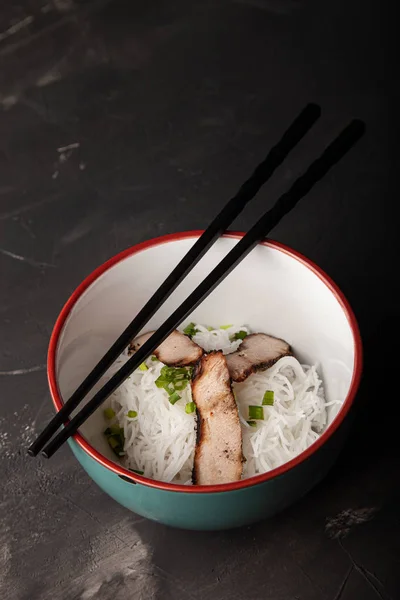 Koostumus kulhoon riisin nuudeleita, lihaa ja vihanneksia — kuvapankkivalokuva