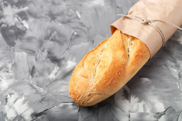 Composition with a bread on a textured plastered surface.