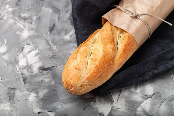 Composition with a bread on a textured plastered surface.