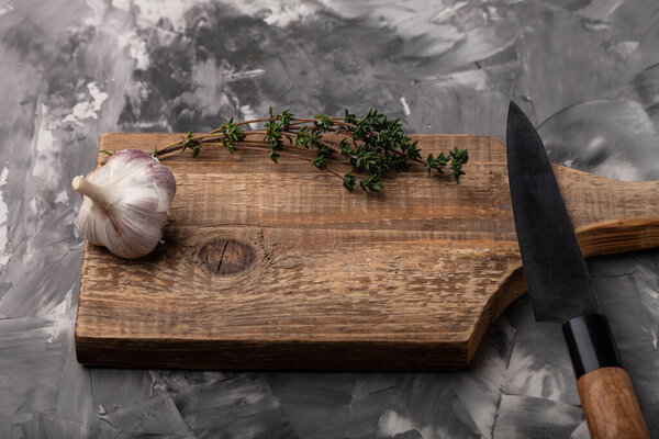 Composition with a garlic and knife on a textured plastered surface.