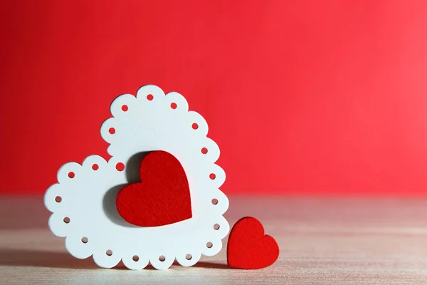 Valentine's Day, wedding, love. White and red bright openwork wooden hearts on a red background with an empty space for writing a congratulatory text or an invitation. — Stock Photo, Image